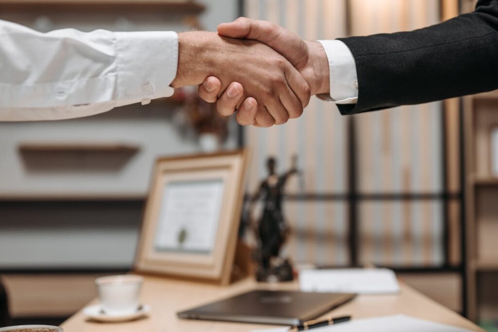 pexels-photo-8112172 Close-up of a handshake between two professionals in a modern office setting, emphasizing partnership and agreement.