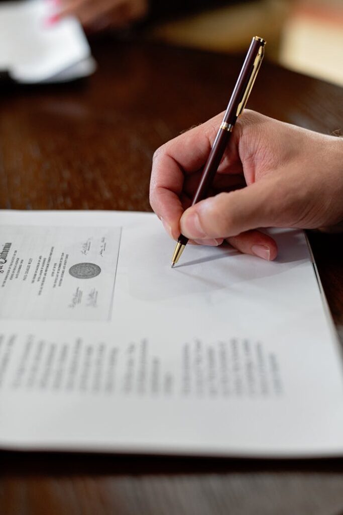 pexels-photo-8730982 A detailed close-up photo of a hand signing a formal document with a pen, creating a professional agreement.